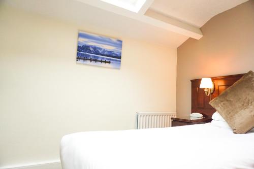 a bedroom with a bed and a picture on the wall at Manor House Hotel, Cockermouth in Cockermouth