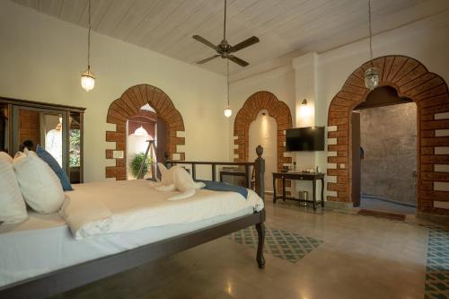 ベノーリムにあるSilva Heritage Resort Goaのアーチのある部屋にベッド1台が備わるベッドルーム1室が備わります。