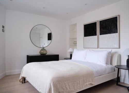 a white bedroom with a large bed and a mirror at Stunning Marylebone apartment in London