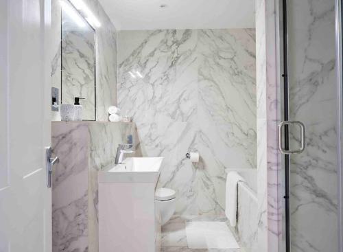 a white bathroom with a toilet and a sink at Stunning Marylebone apartment in London