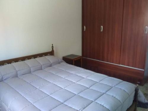 a white bed in a bedroom with a wooden cabinet at Alquiler diario in Malargüe