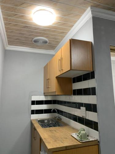 a kitchen with wooden cabinets and black and white tiles at northmead lodge in Benoni