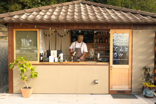 a man is standing at a counter in a bar at てんとうみ 渋川海岸グランピング Tentoumi Shibukawa Beach Glamping in Tamano