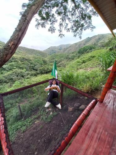 a woman sitting on a fence in the mountains at La Bota del Gigante in Gigante