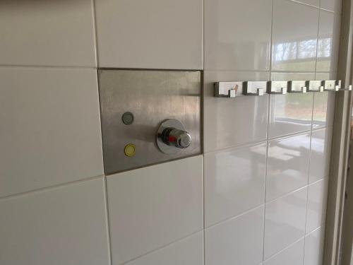 a white tiled shower with a metal door at Vakantiehuisje drenthe gasselterveld in Gasselte