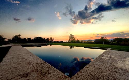a pool of water with a sunset in the background at Natiia Relais - Adults Only in Lazise