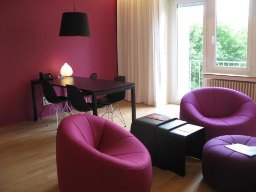 a living room with purple chairs and a table at Key Inn Appart Hotel Parc de Merl in Luxembourg