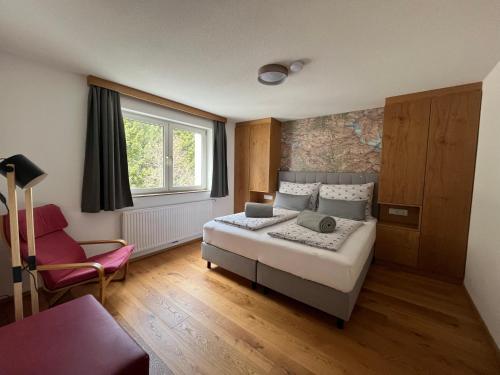 um quarto com uma cama, uma cadeira e uma janela em Apartments Hohenberger em Mallnitz