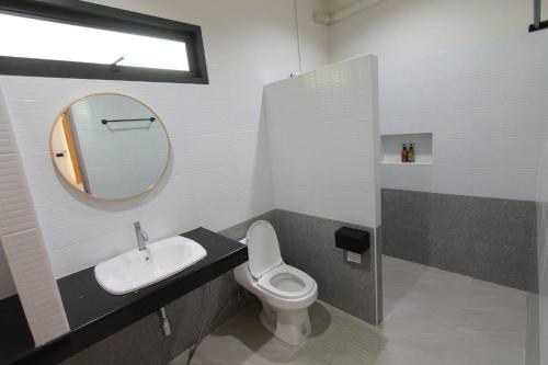 a bathroom with a toilet and a sink and a mirror at Nararin Garden House in Ban Nong Sa