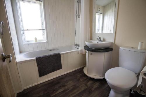 a bathroom with a toilet and a sink and a tub at Luxury Lodge With Full Sea Views At Azure Seas In Suffolk Ref 32105og in Lowestoft