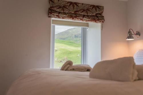 a person laying on a bed looking out a window at Fellside Cottage Coppermines Valley in Coniston