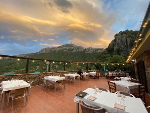 a restaurant with tables and a mountain in the background at Hotel Sant'elene in Dorgali