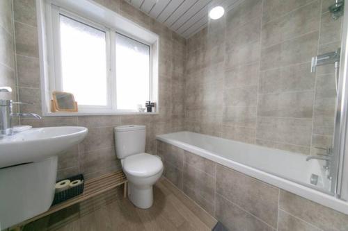 a bathroom with a toilet and a tub and a sink at Lancashire Living! in Preesall