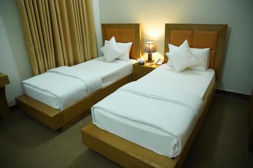 two beds in a hotel room with white sheets at Hotel Red Line in Islamabad