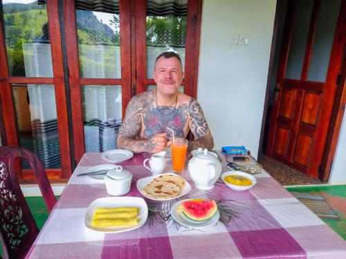 a man sitting at a table with food and drinks at Ella Happy View Homestay in Ella