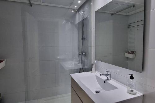 uma casa de banho com um lavatório e um chuveiro com um espelho. em Habitación Privada en el Centro de Madrid em Madri
