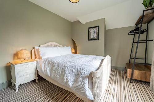 a bedroom with a white bed and a night stand at 3-Bedroom Cottage with Parking Sleeps 6 in Harlow