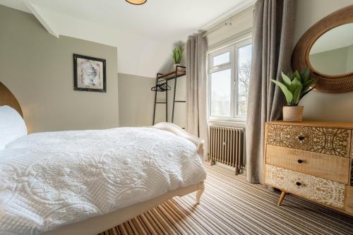 a bedroom with a bed and a mirror and a dresser at 3-Bedroom Cottage with Parking Sleeps 6 in Harlow