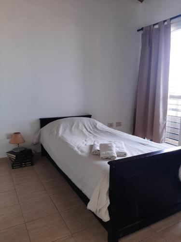 1 dormitorio con 1 cama con sábanas blancas y ventana en Departamentos Angenino Lujan en Luján de Cuyo