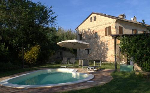 a swimming pool with an umbrella and chairs and a house at Casa il Girasole con piscina nelle Marche in Macerata