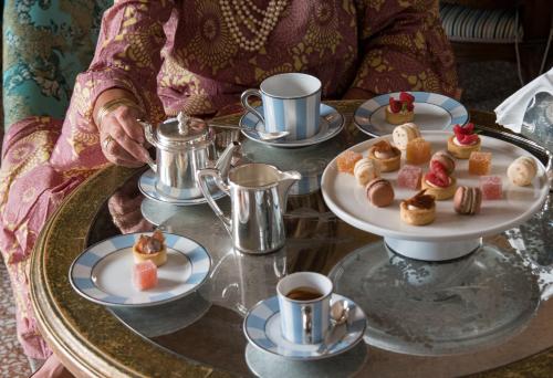 a woman sitting at a table with a tray of desserts at The Gritti Palace, a Luxury Collection Hotel, Venice in Venice