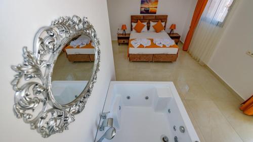 ein Bad mit einer Badewanne und einem Spiegel sowie ein Schlafzimmer in der Unterkunft Atlantis - 4 Bedroom Holiday Villa in Hisaronu in Oludeniz