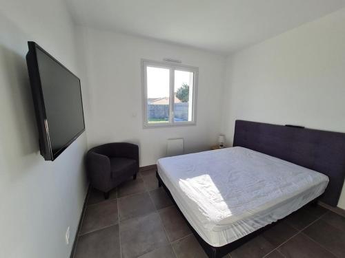 une chambre avec un lit, une chaise et une télévision dans l'établissement MAISON RECENTE 58 ABBAYE, à Saint-Jean-de-Monts