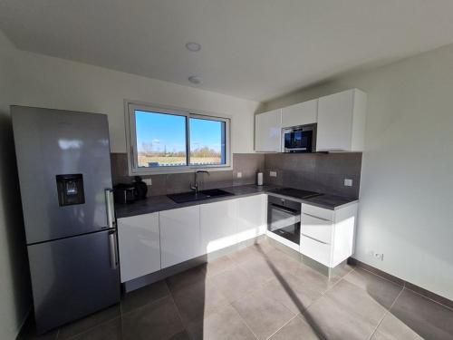 une cuisine avec des armoires blanches et un réfrigérateur en acier inoxydable dans l'établissement MAISON RECENTE 58 ABBAYE, à Saint-Jean-de-Monts