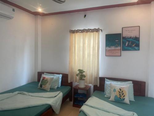 - une chambre avec 2 lits et une fenêtre dans l'établissement Nhà nghỉ Phương Dung, à Duong Dong