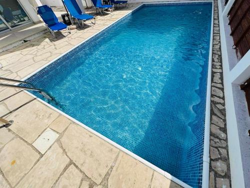 a large blue swimming pool with blue chairs in it at Villa Mulberry Retreat 0,5Km From Everything in Coral Bay