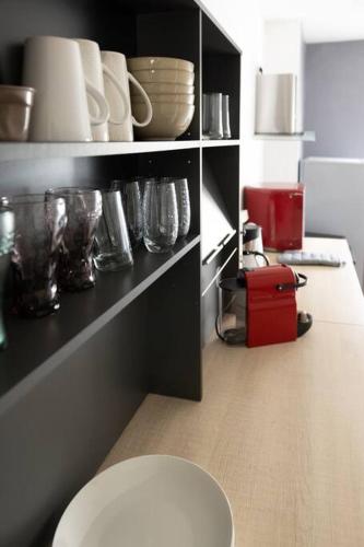 a kitchen with a shelf with bowls and glasses at Magnifique T2 avec balcon centre-ville in Cognac