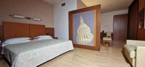 ein Schlafzimmer mit einem Bett und einem Bild eines Gebäudes in der Unterkunft Bella Italia Palace Hotel in Novara