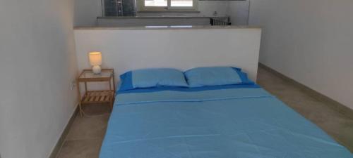 a blue bed in a white room with a window at Casa Leukos Salento - con terrazza privata in Vignacastrisi