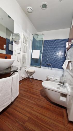 a bathroom with a sink and a tub and a toilet at Bella Italia Palace Hotel in Novara
