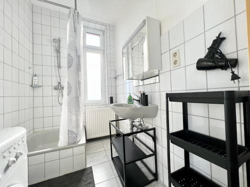 La salle de bains blanche est pourvue d'un lavabo et d'une baignoire. dans l'établissement Großes Apartment Bremerhaven, à Bremerhaven