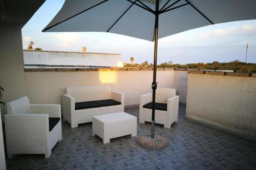 um pátio com uma mesa, cadeiras e um guarda-sol em Casa Leukos Salento - con terrazza privata em Vignacastrisi
