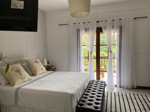 a bedroom with a bed and a large window at Casa Boutique in Cunha