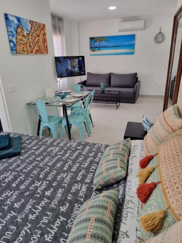 uma sala de estar com uma cama e uma mesa em APARTAMENTOS ELEMAR em Málaga