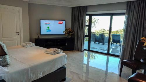 a bedroom with a bed and a flat screen tv at The View Boutique Hotel & Spa in Amanzimtoti