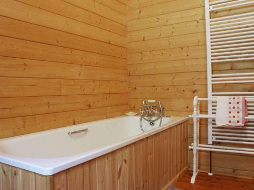 baño con bañera y pared de madera en Valley Lodge, en Tiverton