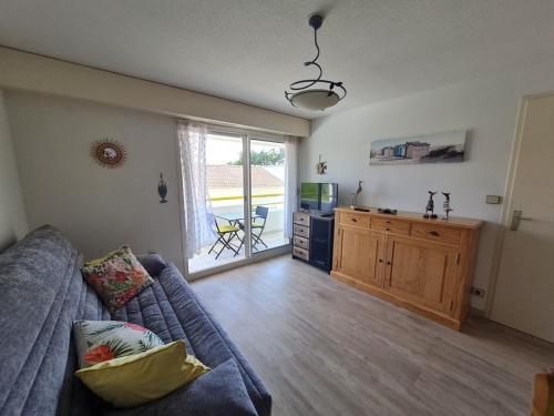 un salon avec un canapé bleu et une cuisine dans l'établissement 2 PIECES RUE DES GENETS, à Saint-Jean-de-Monts