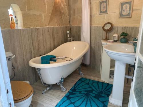 a bathroom with a tub and a sink and a toilet at Traditional Maltese House in centre of Town in Mosta