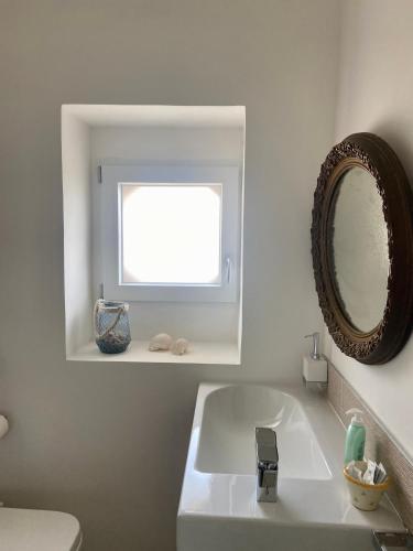 Baño blanco con lavabo y espejo en VillaGio, en Ceglie Messapica