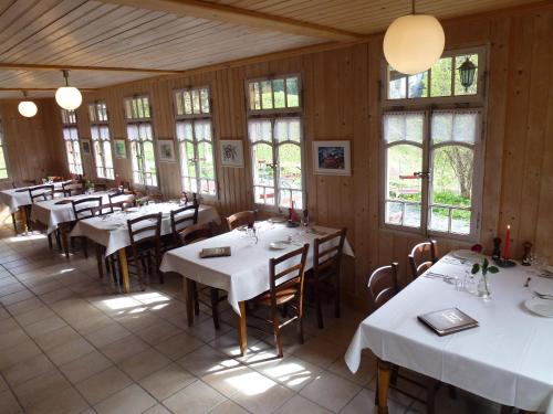 uma sala de jantar com mesas, cadeiras e janelas em Hotel Waldrand em Kiental