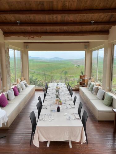 a long table in a room with large windows at Tenuta dei Principi di Spadafora in Bosco Fraccia