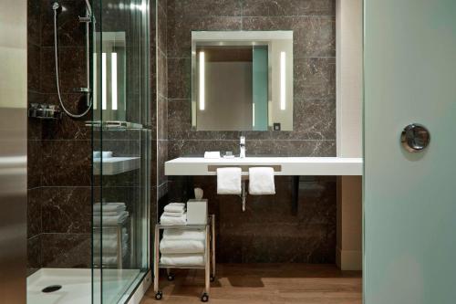 a bathroom with a sink and a glass shower at AC Hotel by Marriott Minneapolis Downtown in Minneapolis