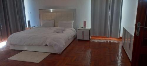 Sequata的住宿－The Hill 4 - Holiday Villa，卧室配有白色的床,铺有木地板