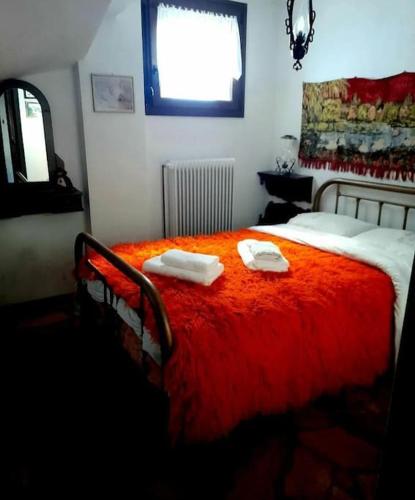 a bedroom with a red bed with two towels on it at Ενοικιαζόμενη Παραδοσιακή κατοικία Σαν Παραμύθι in Volakas