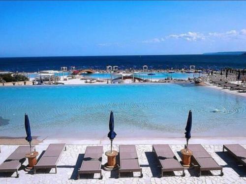 a large swimming pool with chairs and the ocean at Casa Leukos Salento - con terrazza privata in Vignacastrisi