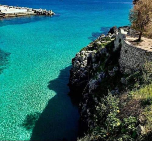a large body of water next to a rock wall at Casa Leukos Salento - con terrazza privata in Vignacastrisi